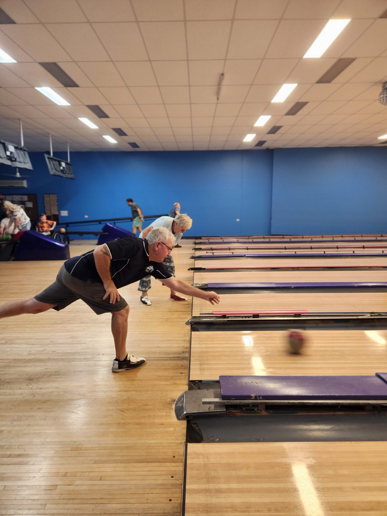 Man releasing bowling ball down lane