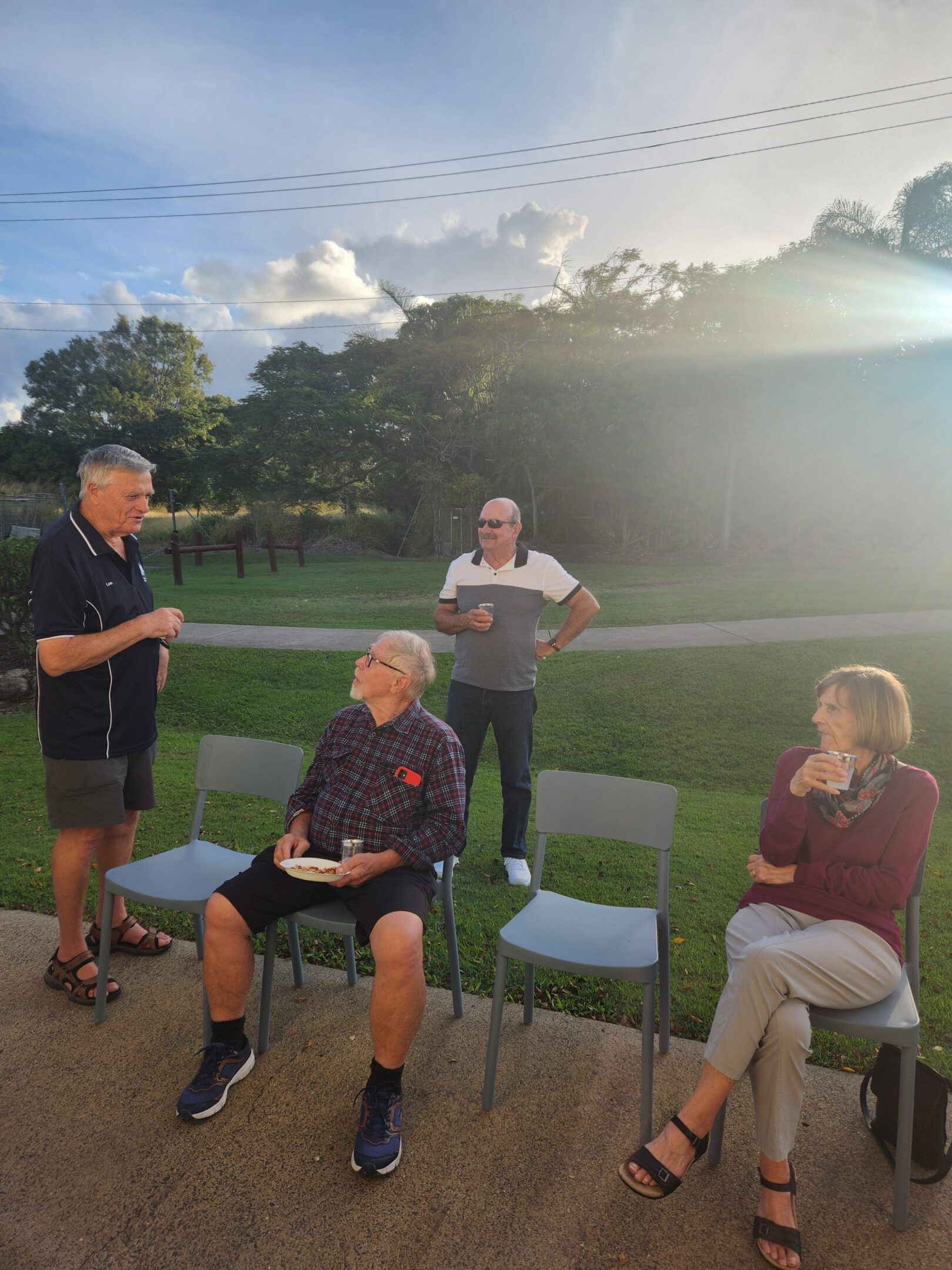 Group of four adults chatting outdoors in sunlight