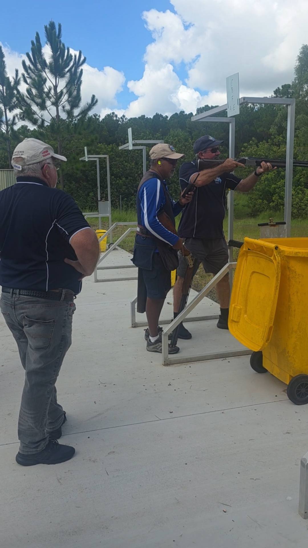 Three men at outdoor shotgun shooting range