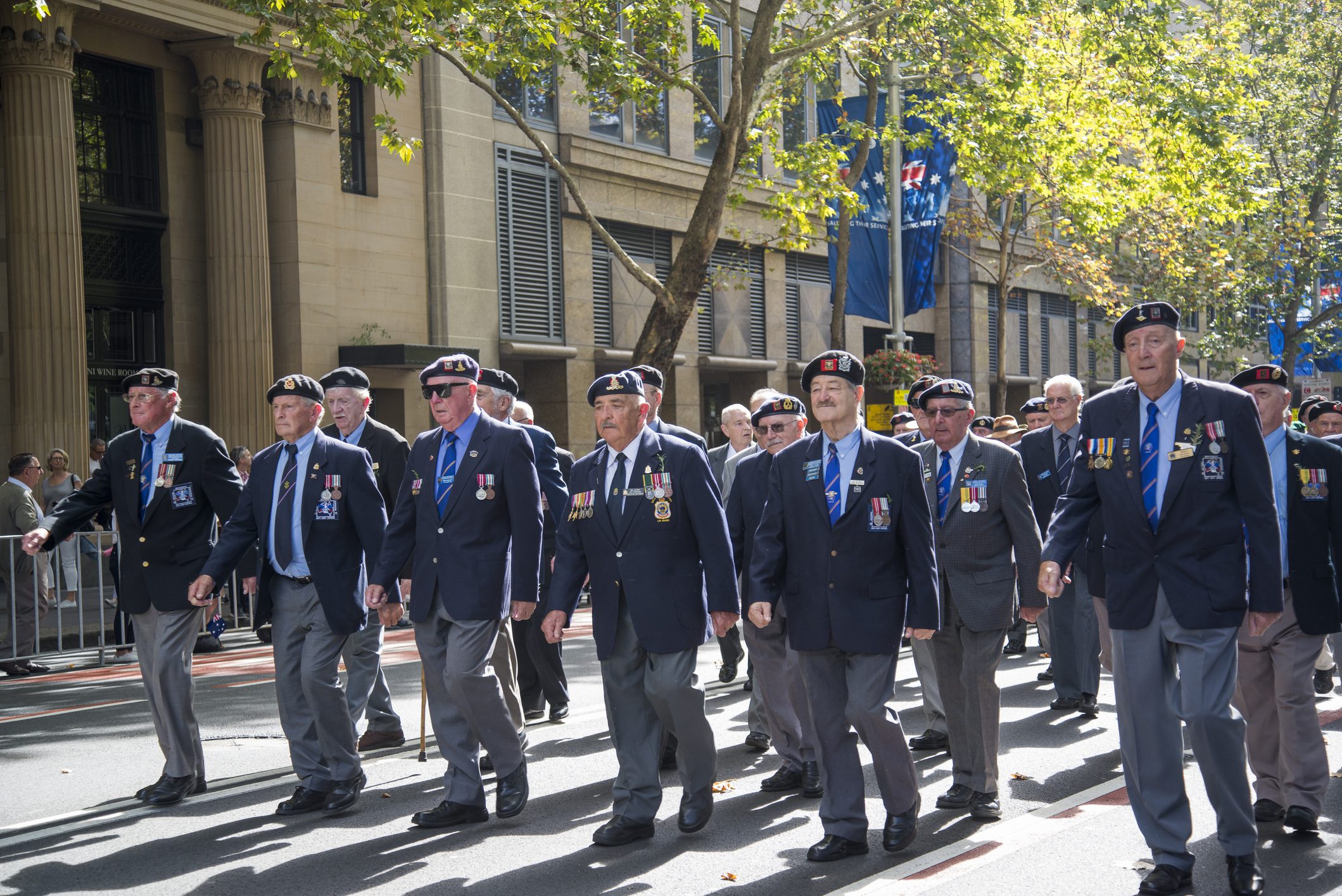 Veterans marching in parade wearing medals and berets