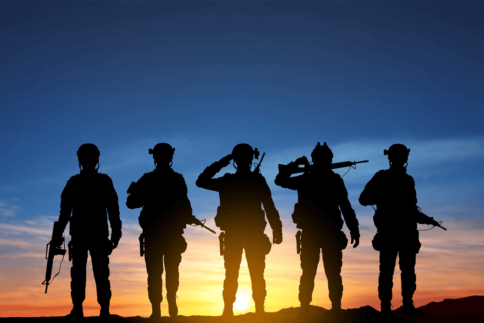 Soldiers silhouetted against sunset sky